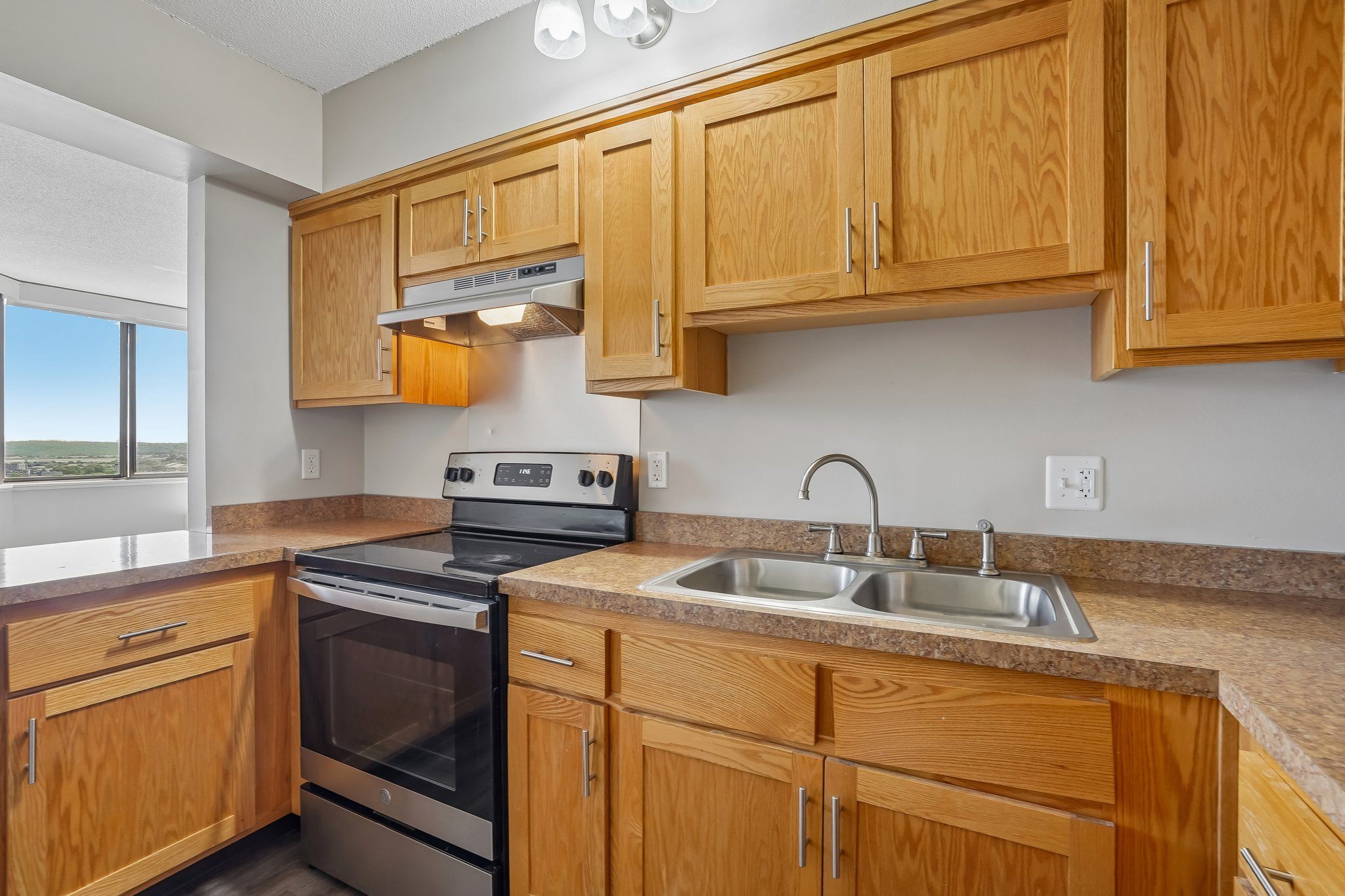 Irvine Park Towers kitchen with wood cabinets, double sink, range and window